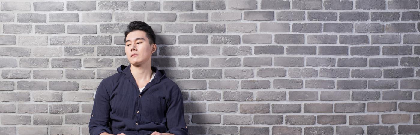 teen boy sitting against wall