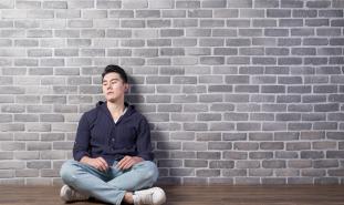 teen boy sitting against wall