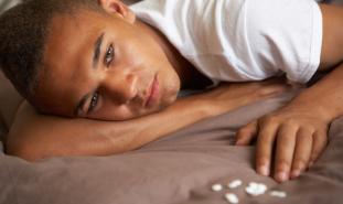 teen laying down with pills